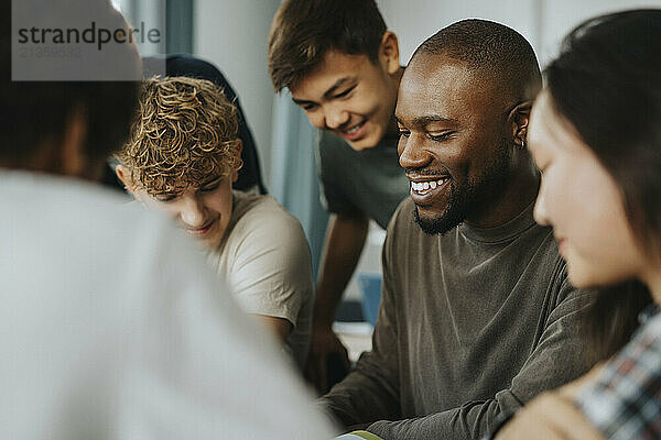 Happy male teacher guiding teenage girls and boys at high school