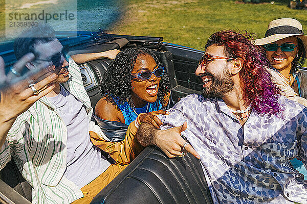 High angle view of cheerful multiracial male and female friends sitting in car at park on sunny day