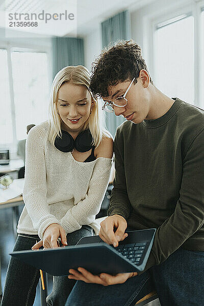 Teenage boy and girl using laptop in classroom at high school