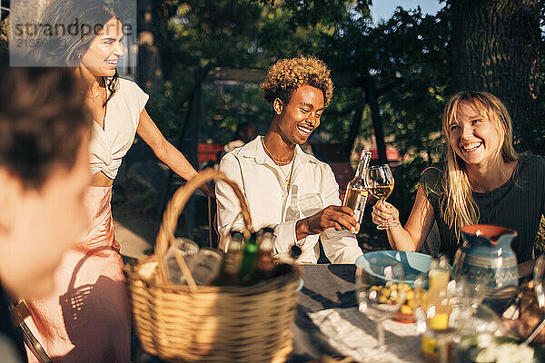 Happy male and female friends toasting drinks during dinner party in back yard