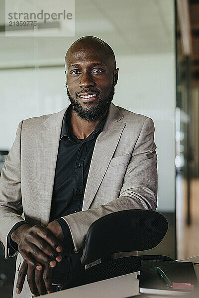 Portrait of smiling businessman leaning on office chair