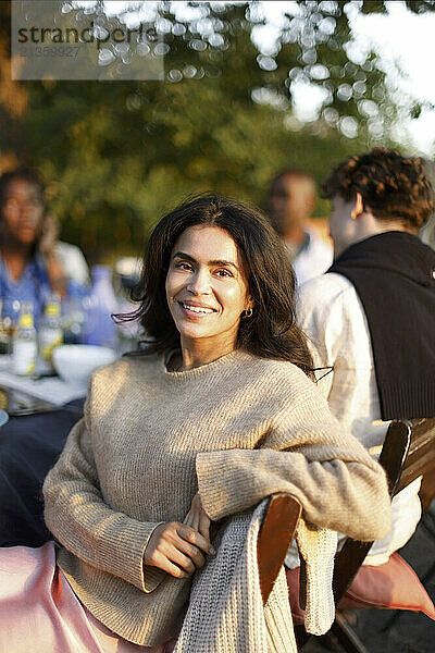 Portrait of smiling woman sitting on chair at social event