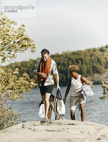 Friends walking over rock after swimming at lake