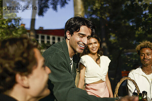 Smiling man enjoying with friends at party in back yard