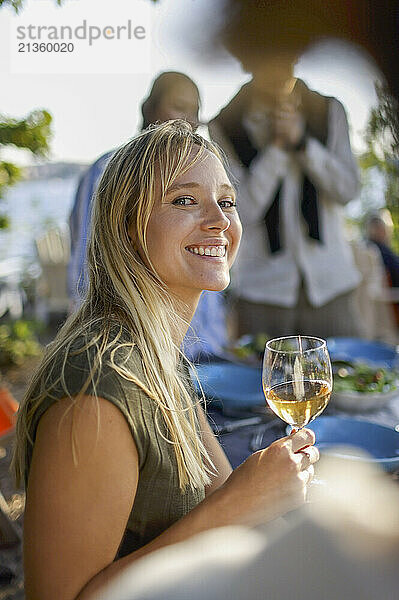 Side view portrait of smiling woman holding wineglass at dinner party