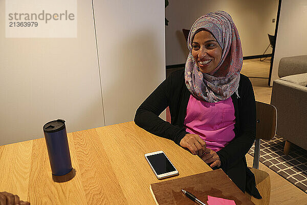 Woman in hijab sitting at table