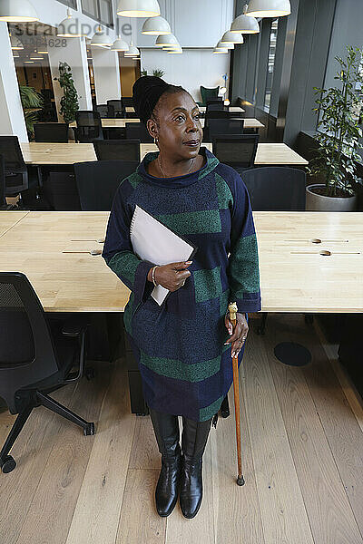 Pensive businesswoman with cane in office