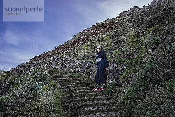 Female tourist stands posing on the steps at the hiking destination Pico do Areeiro on the island of Madeira in Portugal; Sao Roque do Faial  Madeira  Portugal