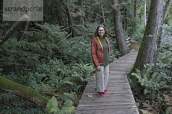 Woman standing on a boardwalk in a rainforest on Vancouver Island  BC  Canada; Saanichton  British Columbia  Canada