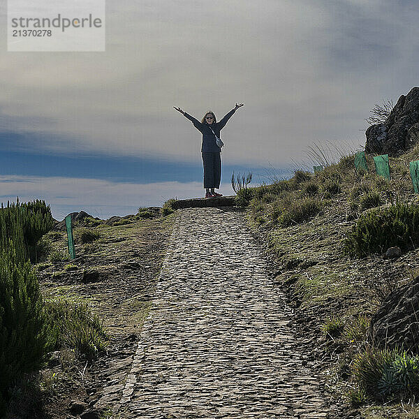 Female hiker celebrates the ascent to Pico do Areeiro  a high altitude hiking destination on the island of Madeira  Portugal; Sao Roque do Faial  Madeira  Portugal