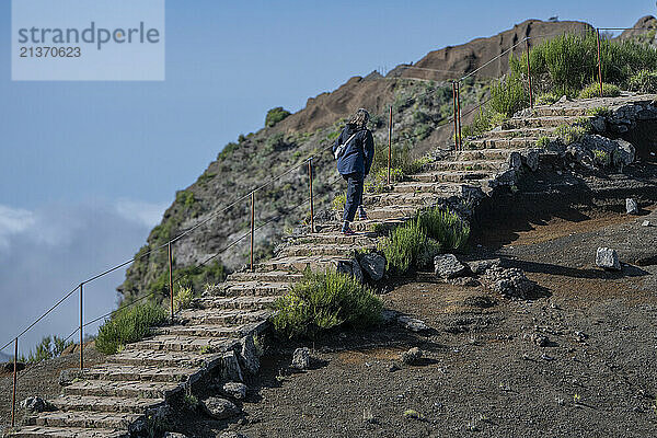 Female tourist ascends the steps of the high altitude hiking destination of Pico do Areeiro on the island of Madeira  Portugal; Sao Roque do Faial  Madeira  Portugal