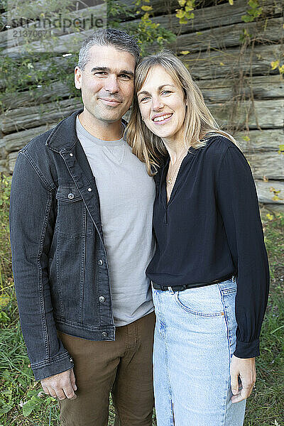 Portrait of a married couple smiling and standing in front of a wooden building in Beckwith Township at Carleton Place in the Ottawa Valley; Ontario  Canada