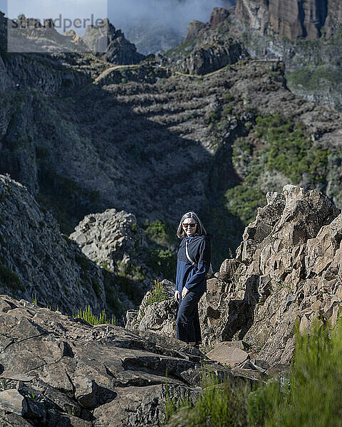 Woman stands on the trail of the rugged Pico Do Areeiro hiking destination on Maderia  Portugal; Sao Roque do Faial  Madeira  Portugal