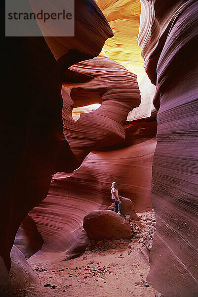 Female tourist stands in a slot canyon  Antelope Canyon  viewing the wavy patterns in the colourful sandstone rock; Arizona  United States of America