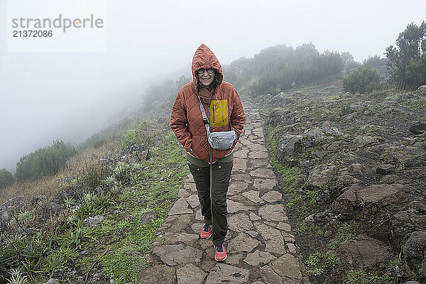 Female tourist on the trail in the fog at the highest peak  Pico Ruivo  on the island of Madeira  Portugal; Ilha  Madeira  Portugal