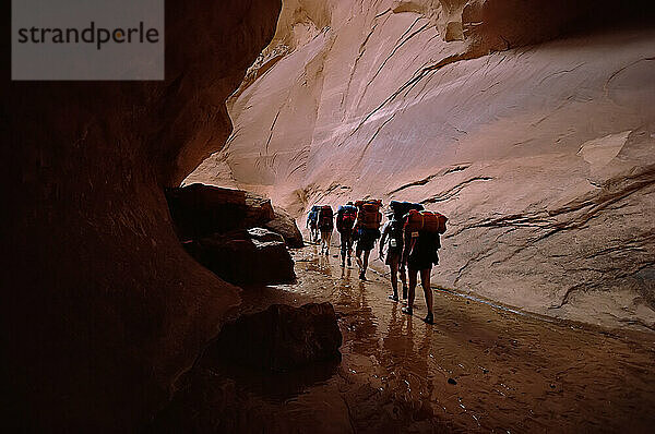 Tourists with backpacks walking through a slot canyon with sandstone rock walls in Arizona  USA; Arizona  United States of America