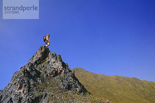 Women hiking across a mountain peak on a clear sunny day in the Ogilvie Mountains of Yukon  Canada; Yukon  Canada