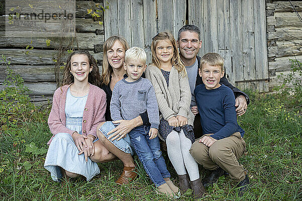 Portrait of a family sitting in front of a wooden building in Beckwith Township at Carleton Place in the Ottawa Valley; Ontario  Canada