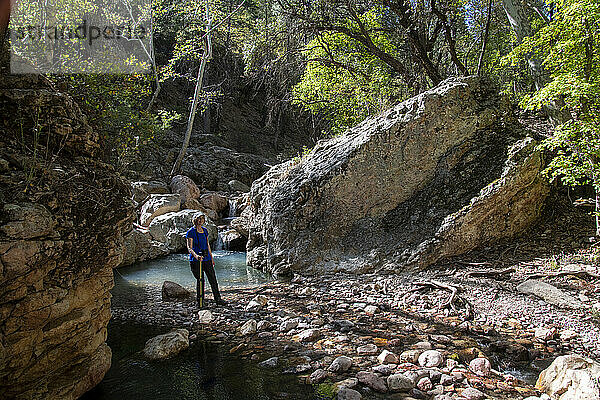 Portrait of a female hiker smiling at the camera while standing by a pool in the South Fork of Cave Creek in the Chiricahua Mountains of Southeast Arizona; Arizona  United States of America