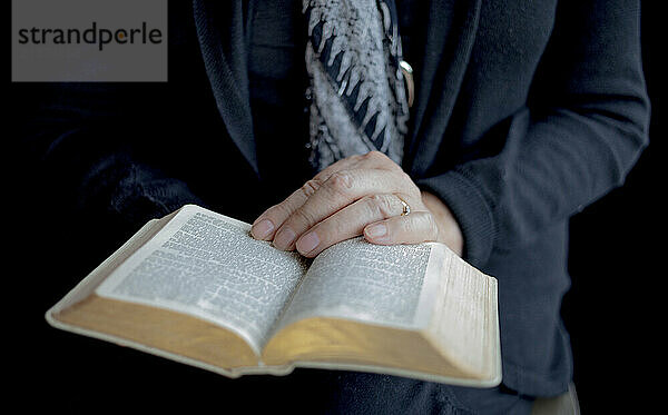 Woman's hands holding an open Bible; Studio