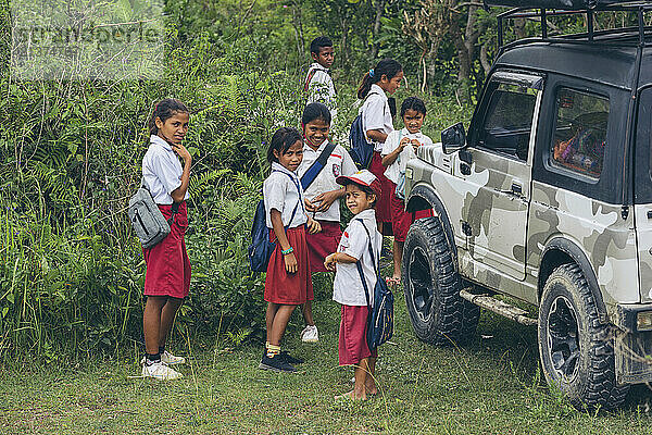 School children standing together by a parked SUV in West Sumba Regency  Indonesia; West Sumba Regency  East Nusa Tenggara  Indonesia