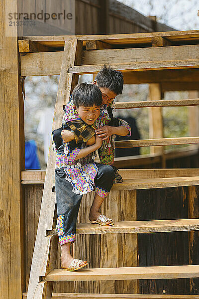 Two boys playing on steps in Vietnam; Ban Nam Nghiep  Muong La  Son La  Vietnam