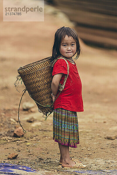 Cute young girl carrying a basket on her back; Ban Nam Nghiep  Muong La  Son La  Vietnam