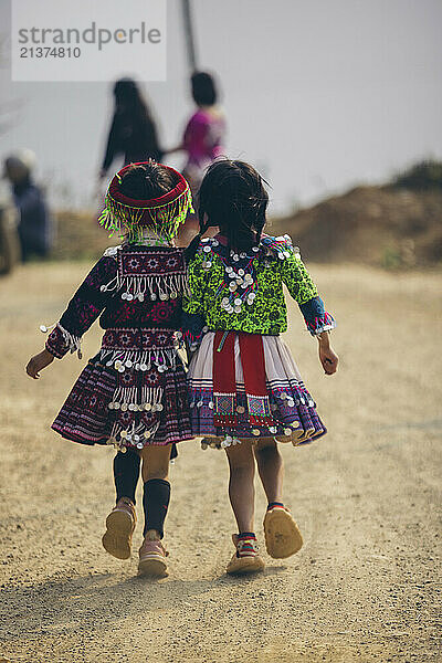 Two young girls walk hand in hand down a country road in Vietnam; Ban Nam Nghiep  Muong La  Son La  Vietnam