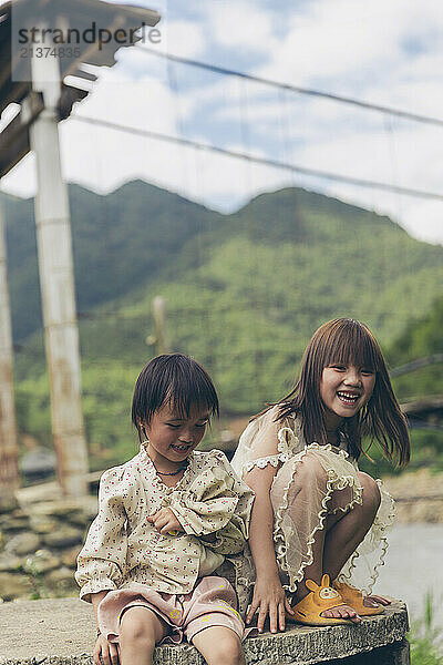 Two young girls spending time together outdoors; Ngoc Chien  Muong La District  Son La  Vietnam