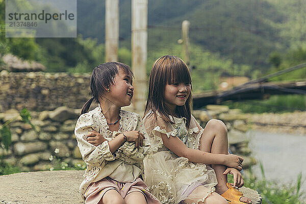 Two young girls spending time together outdoors; Ngoc Chien  Muong La District  Son La  Vietnam