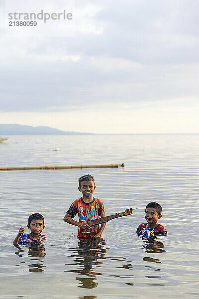 Boys playing in the clear ocean water off the island of Bunaken in Indonesia; Bunaken  North Sulawesi  Indonesia