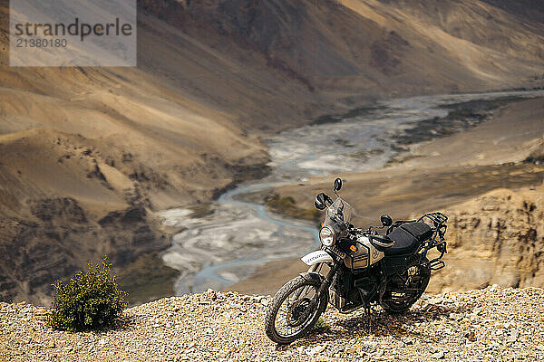 Motorcycle parked at a viewpoint of a river running through a valley in the Himalayas at the remote village of Kaza along Dhar Lung Wooh mountain pass  Spiti Valley  India; Dhar Lung Wooh  Himachal Pradesh  India