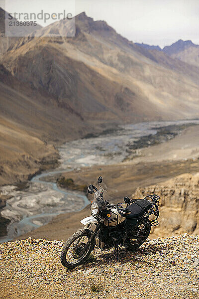 Motorcycle parked at a viewpoint of a river running through a valley in the Himalayas at the remote village of Kaza along Dhar Lung Wooh mountain pass  Spiti Valley  India; Dhar Lung Wooh  Himachal Pradesh  India