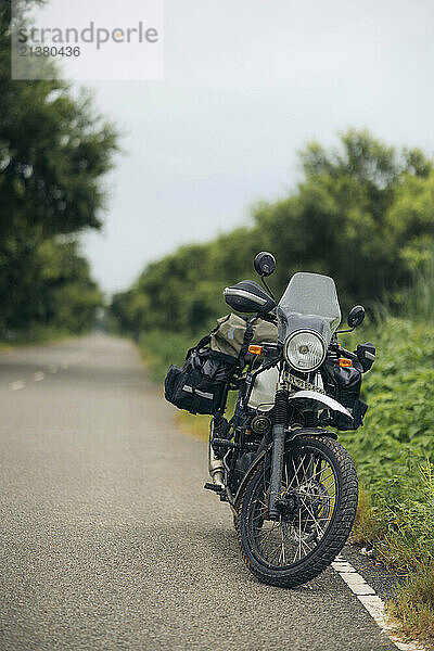 Motorcycle parked along a paved road in Meerut  Uttar Pradesh  India; Meerut  Uttar Pradesh  India