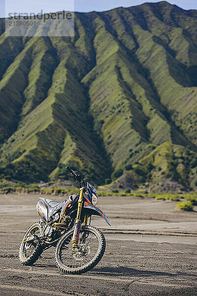 Motorbike parked on the sand on a sunny day in Bromo Tengger Semeru National Park  with the Tengger Massif in the background  East Java  Indonesia; Ranupani  East Java  Indonesia