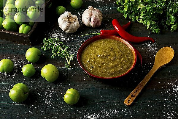 Tkemali sauce  traditional Georgian cuisine  green cherry plum  with ingredients for sauce  cilantro  mint  hot pepper  garlic  on a wooden table  close-up  rustic  food background  no people  selective focus  sauce  green sauce  tkemali  georgian cuisine  homemade