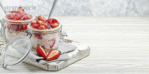 Parfait with Fresh Strawberries  Yoghurt and Crunchy Granola in Transparent Glass Mason Jars on White Rustic Wooden Background Angle View  Healthy Breakfast or Light Summer Dessert  Copy Space  food photography  food photography