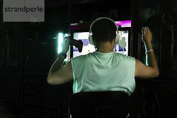 Back portrait of a man celebrating victory while playing video games at home