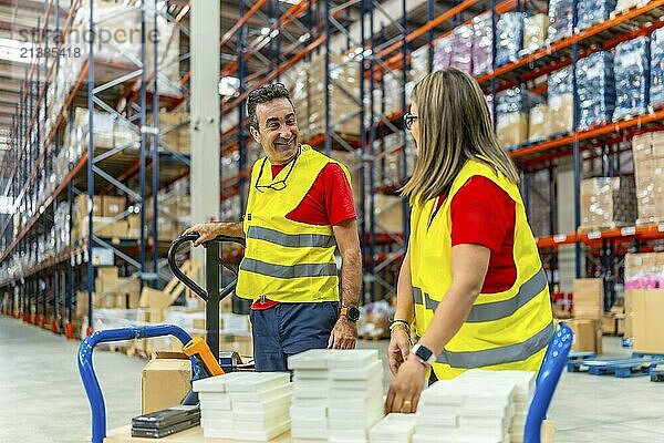 Wide view photo of two male and female happy workers talking while working in distribution warehouse