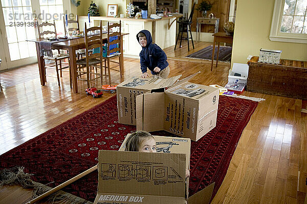 Children play with old cardboard boxes at their home in the Maine countryside.