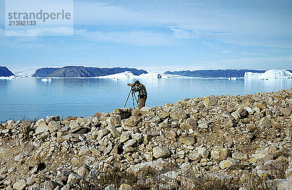 A man photographs sea kayakers hunting for Narwhal in a fjord near the village of Quannaq  Greenland. (releasecode: DM_MR1047)