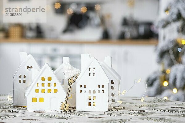 Key and tiny house of a small size on cozy home with Christmas decor on table of festive white kitchen. Gift for New Year. Insurance  moving to new house  mortgage  rent and purchase real estate