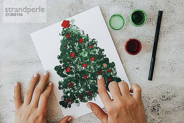 DIY Making greeting card Handmade crafts on holiday for children. Paint with fingers Merry Christmas tree. Top view. Step by step. Do it yourself. Happy New Year xmas tree decoration