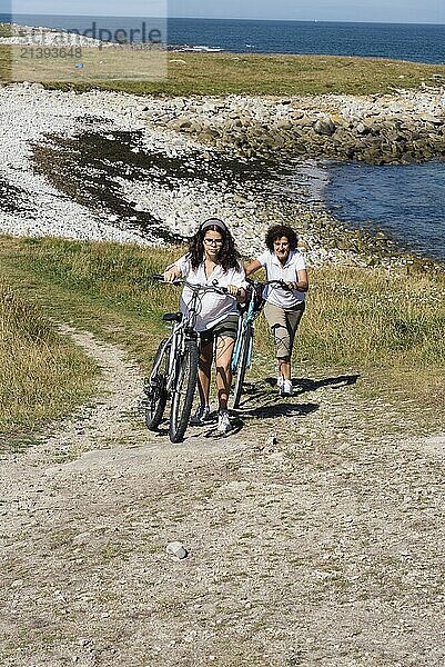 Mother and daughter ride bicycles enjoying the views of landscape in the Island of Batz