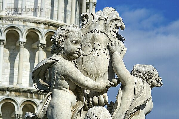 Cherub statue that sits on the Field of Miracles in Pisa Italy with the leaning tower in the background