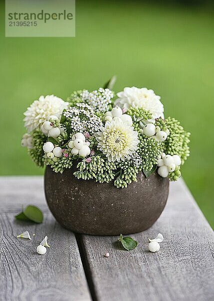 Beautiful bouquet with white dahlias  stonecrop (Sedum) flowers  snowberries (Symphoricarpos) branches in a rustic vase. Simple  handmade decoration