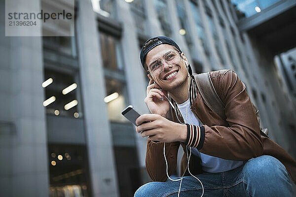 Man Sitting Listening Music Earphones Concept. Cheerful young guy listening the music