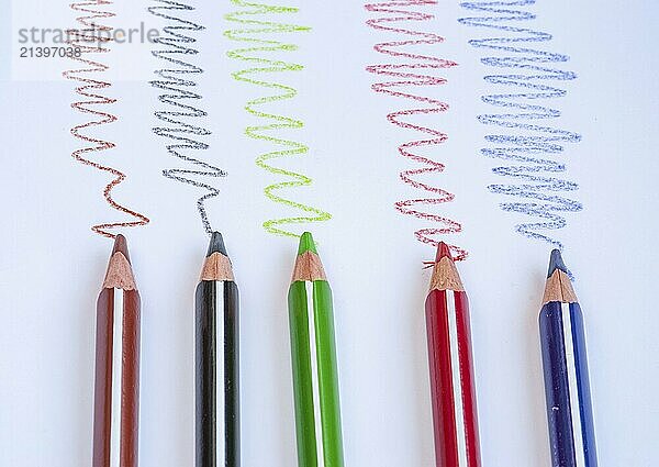 Colour drawing wooden pencils and colourful curved lines on a white paper