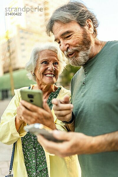 Vertical close-up of a happy senior couple walking using mobile phone in the city