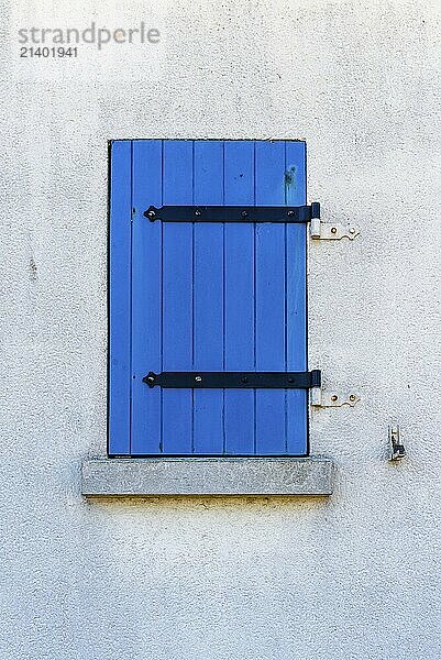 Old window with wooden blue painted shutter on white painted wall